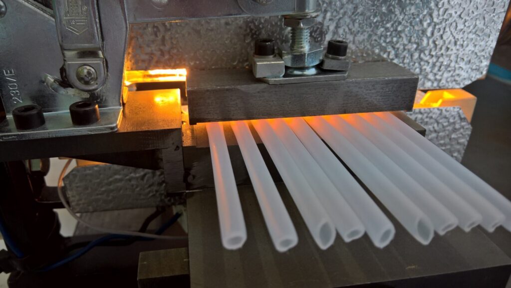 Metallische Vorrichtung mit erhitzten Bereichen, unter der mehrere weiße Kunststoffrohre geführt werden